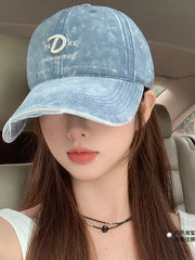 Blue denim baseball cap with embroidered D and text detail, distressed brim.
