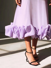 Lavender midi dress with a dramatic ruffle hem, shown with black heeled sandals.