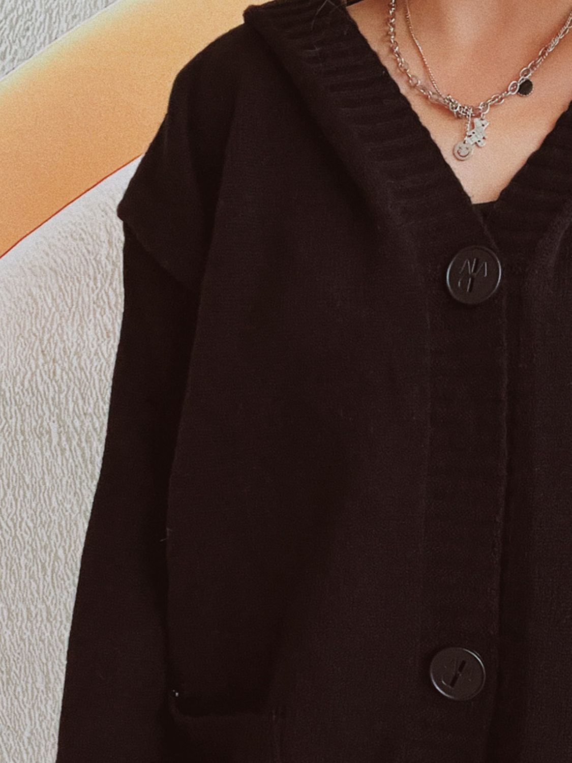 Black chunky knit hooded cardigan with button-down front and ribbed neckline detail.