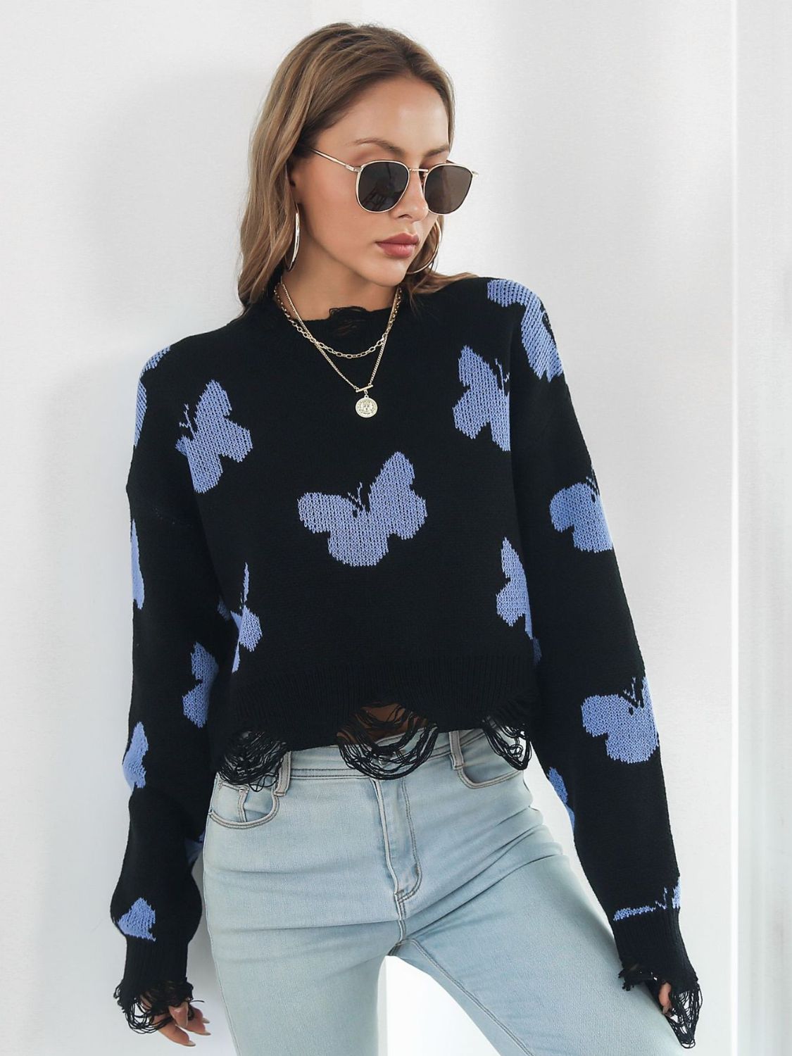Black cropped knit sweater with distressed butterfly print and frayed hem.