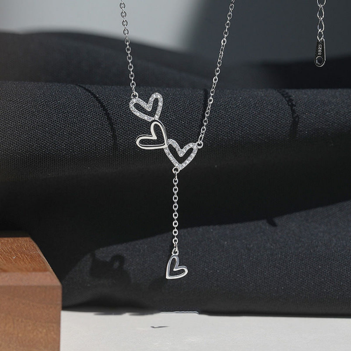 Sterling silver Y-necklace with three intertwined heart charms, two with pave crystals.