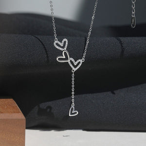 Sterling silver Y-necklace with three intertwined heart charms, two with pave crystals.