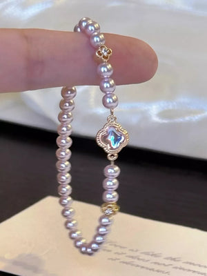 Delicate pearl bracelet with clover charm and gold accents.