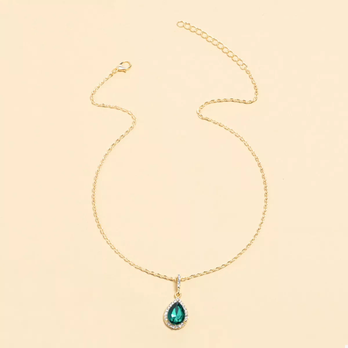Elegant teardrop pendant necklace in dark green with 18K gold-plated chain and crystal accents.