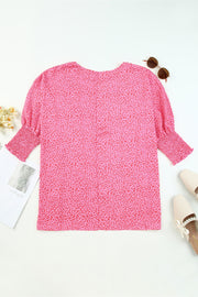 Pink leopard print blouse with smocked sleeves and a scoop neckline.