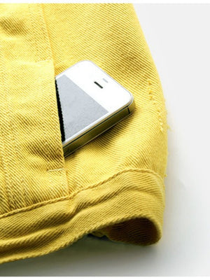 Yellow denim vest with frayed shoulder detail and pocket holding a phone