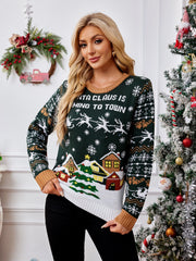 Festive graphic knit sweater in black forest with Santa Claus text and winter village scene.