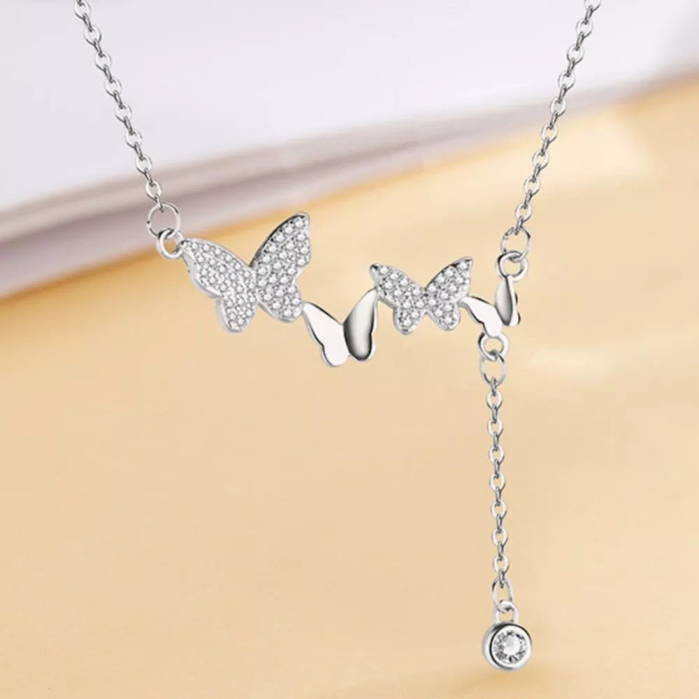 Silver necklace with three butterflies adorned with zircon accents and a dangling charm.