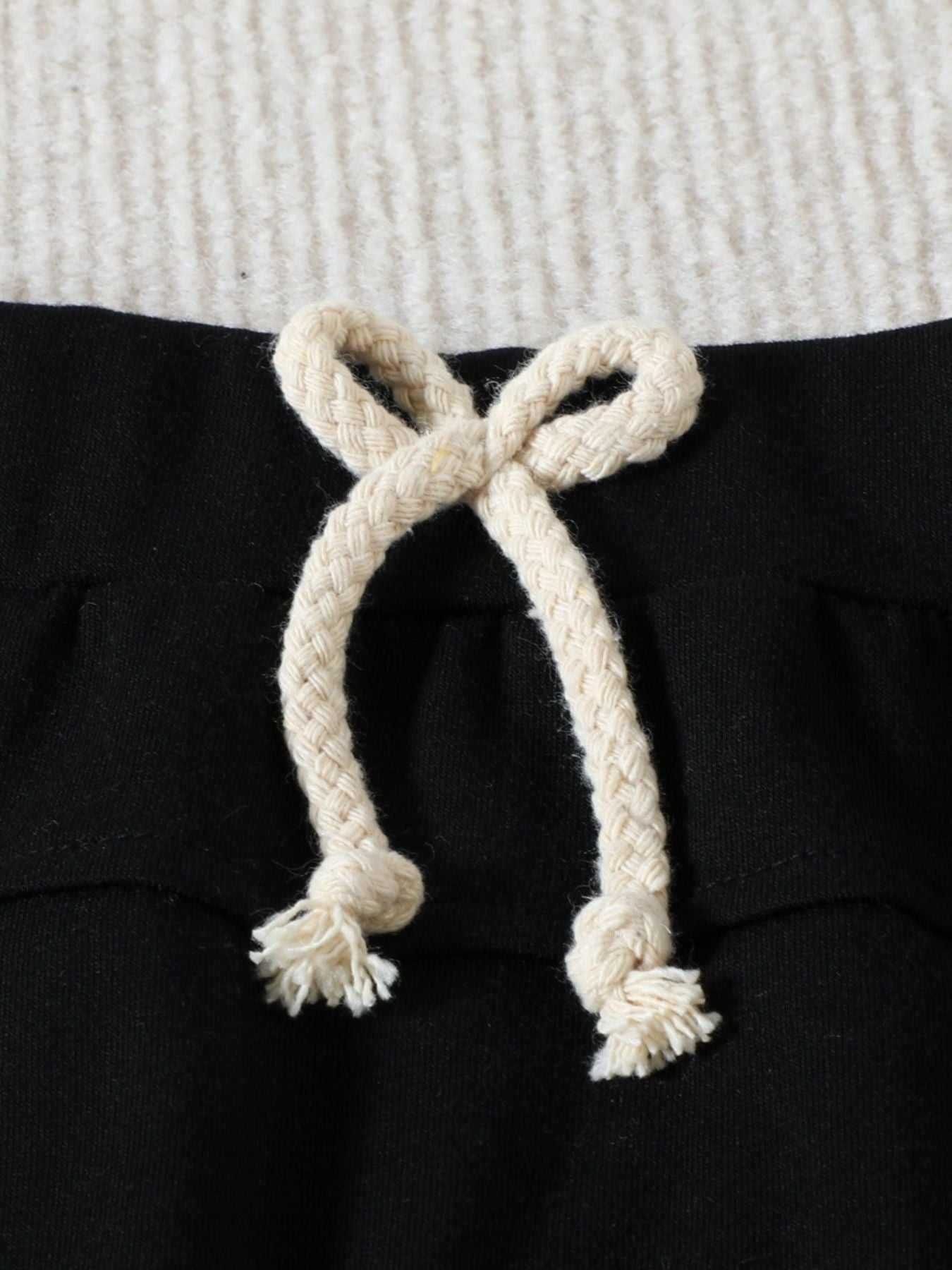 Black cotton baby set shorts with cream drawstring and frayed ends.