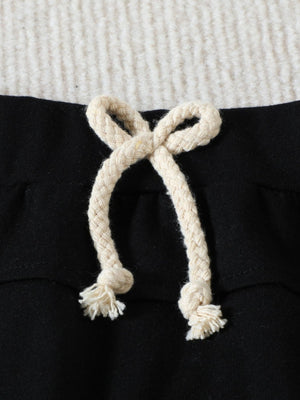 Black cotton baby set shorts with cream drawstring and frayed ends.