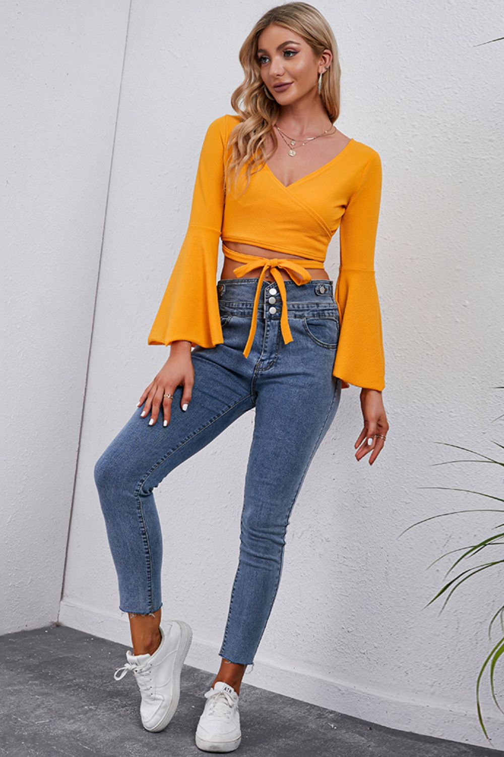 Wrap tie bell sleeve crop blouse in pumpkin orange with a V-neck and tie waist detail.