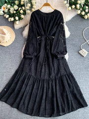 Black embroidered tie-waist midi dress with sheer sleeves and tiered skirt.