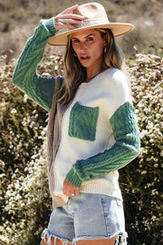 Textured panel pocket sweater in cream with green sleeves and pocket, featuring cable knit details.