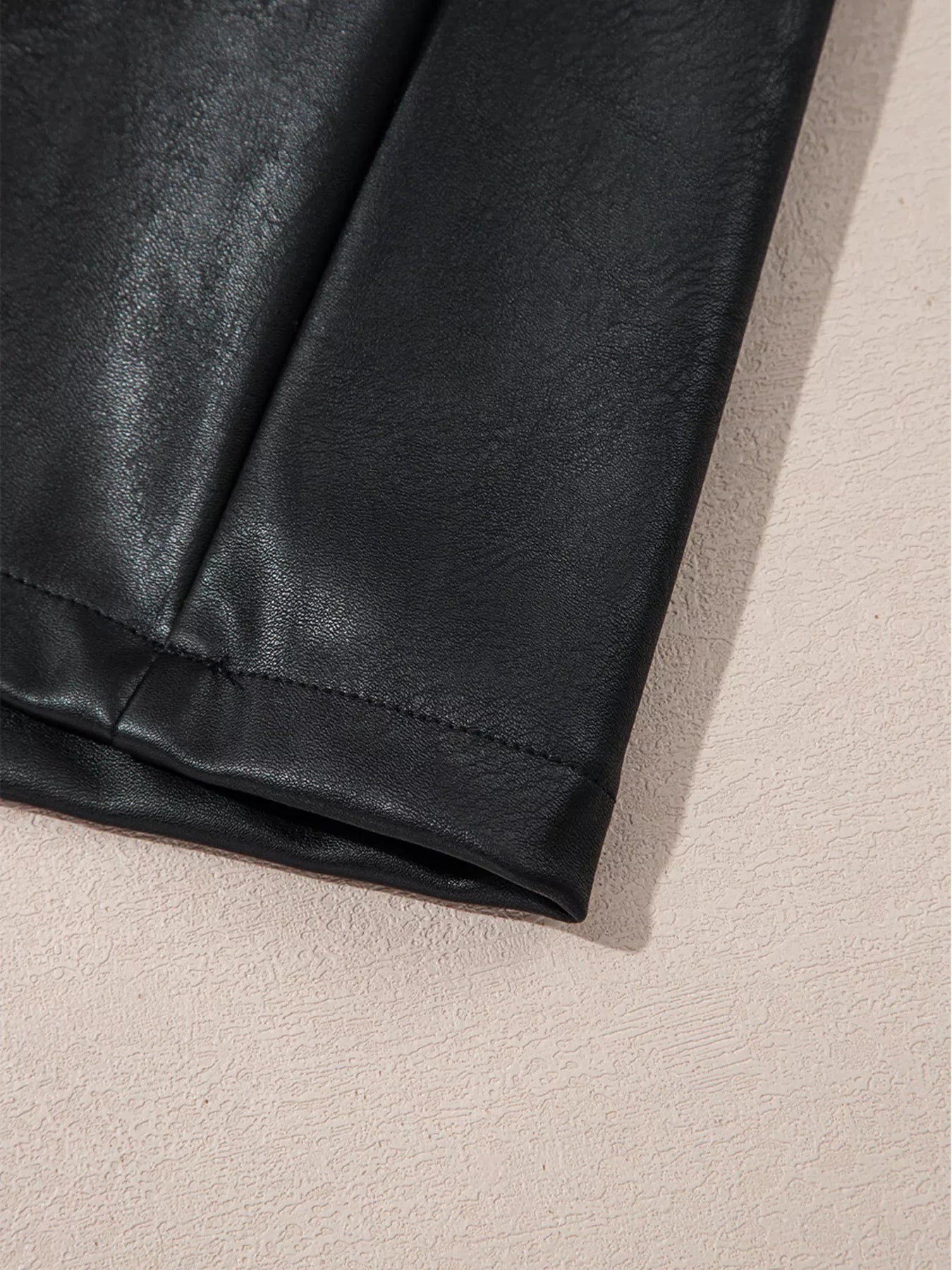 Black vegan leather sleeveless mini dress hem detail