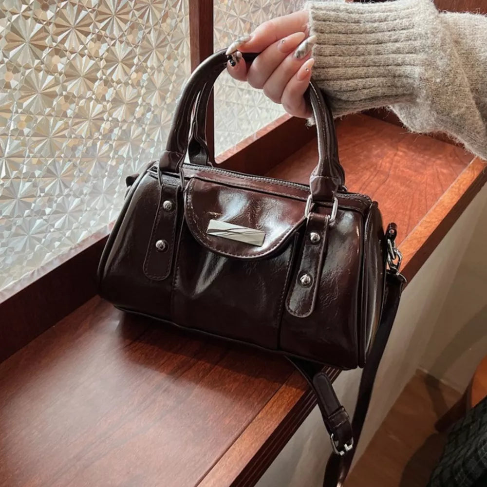 Elegant barrel crossbody bag in brown with top handles and silver hardware.