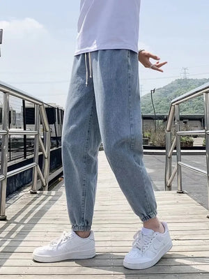 Light blue relaxed fit jeans with drawstring waist and cuffed ankles on a man.