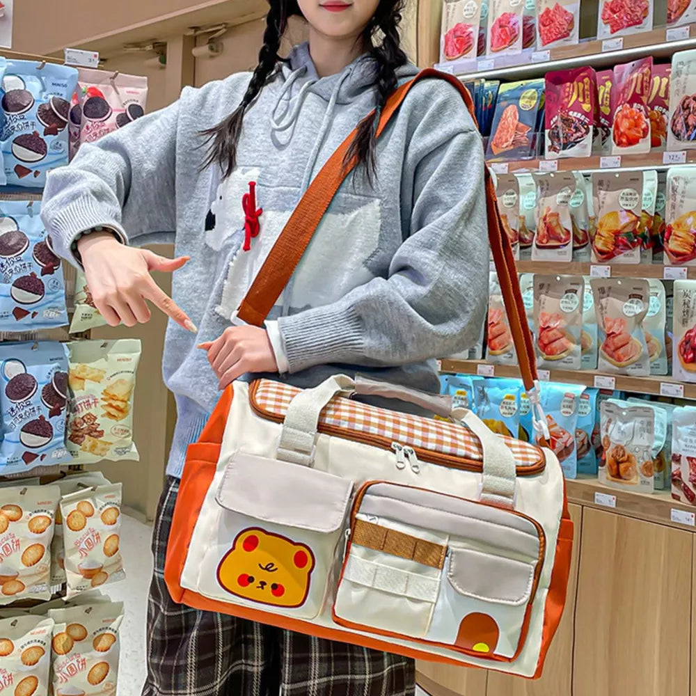 Cream travel bag with orange trim, gingham pattern, and cute bear applique.