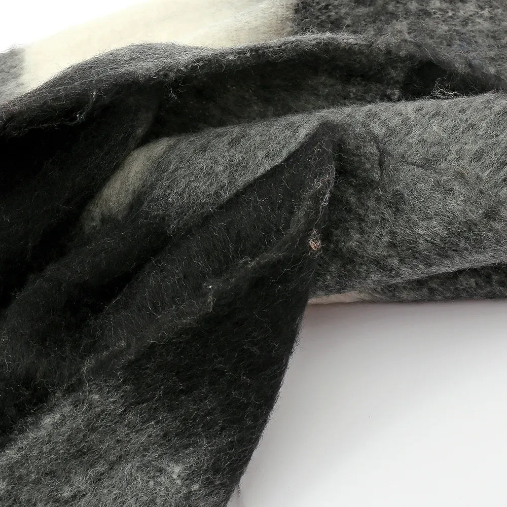 Checked plaid fluffy scarf in black and grey with white accents and fringe detail.