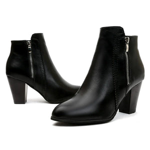 Black leather block heel booties with side zippers and laser-cut detail.