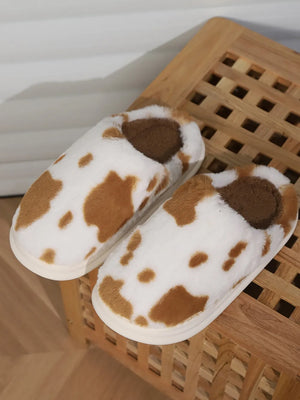 Cow print faux fur house slides in camel and white with brown accents.