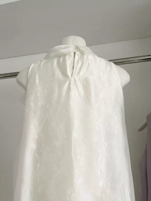 Sleeveless white shirt with subtle floral pattern and back zipper detail.