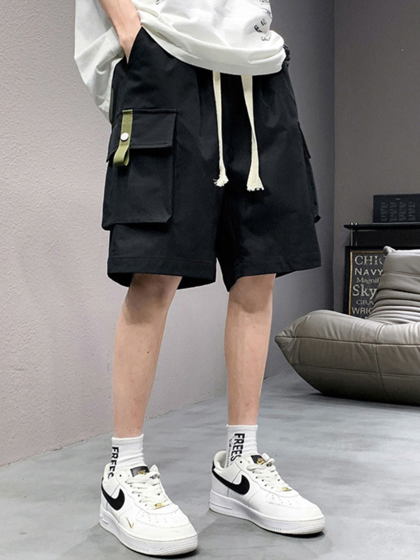 Men's black lightweight cargo shorts with drawstring and green tab detail.