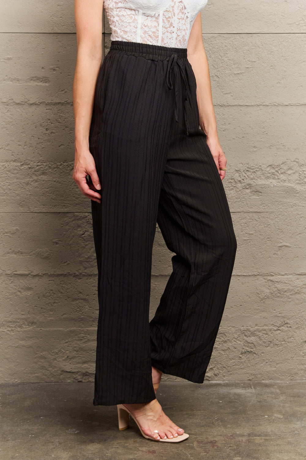 Black ribbed drawstring palazzo trousers with a wide leg.