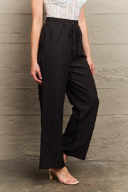Black ribbed drawstring palazzo trousers with a wide leg.