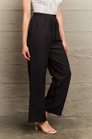 Black ribbed drawstring palazzo trousers with a wide leg.