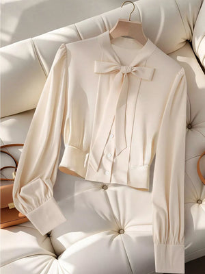 Apricot bow tie blouse with long sleeves and button-down front.