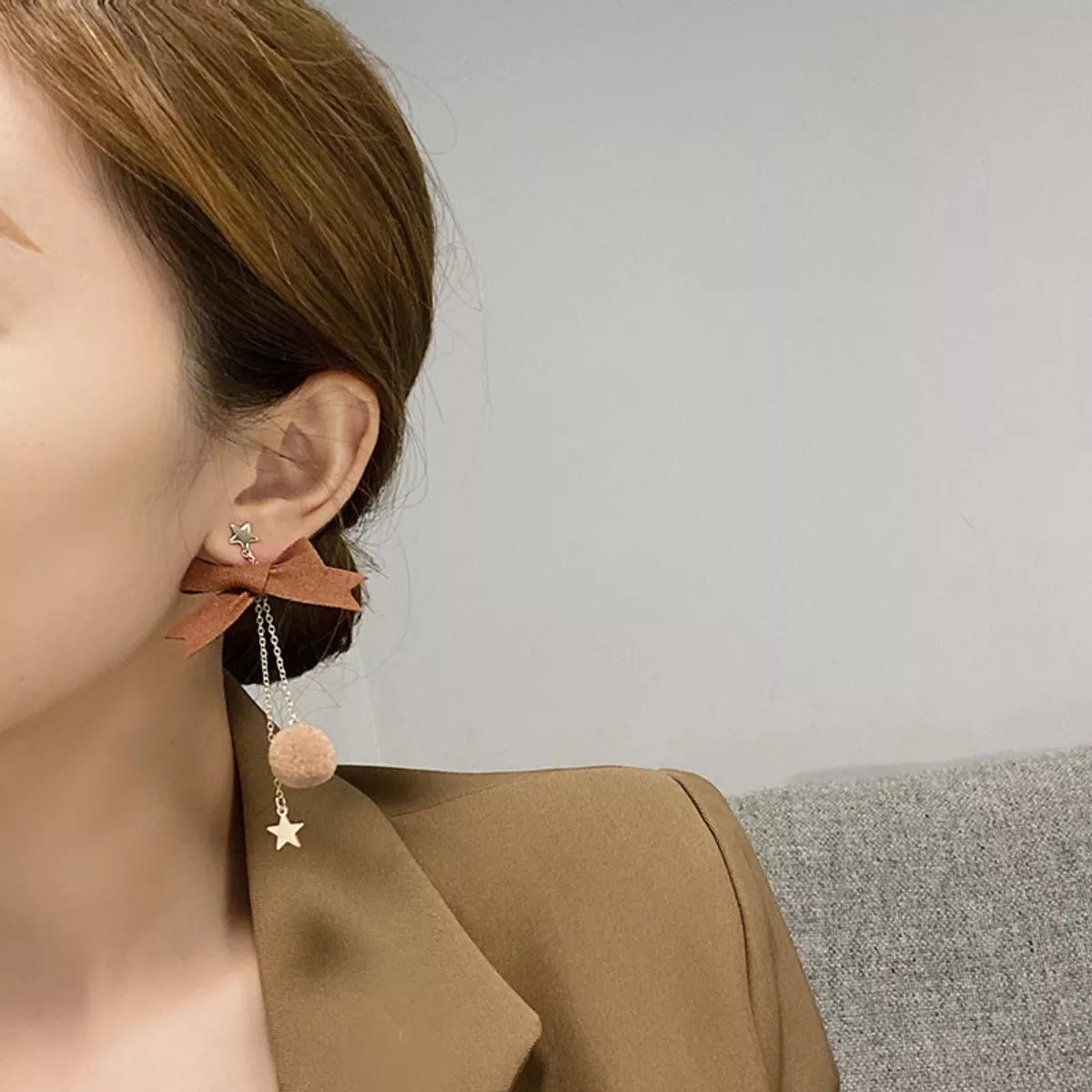 Reindeer bowknot drop earrings in camel with star and pompom charms.