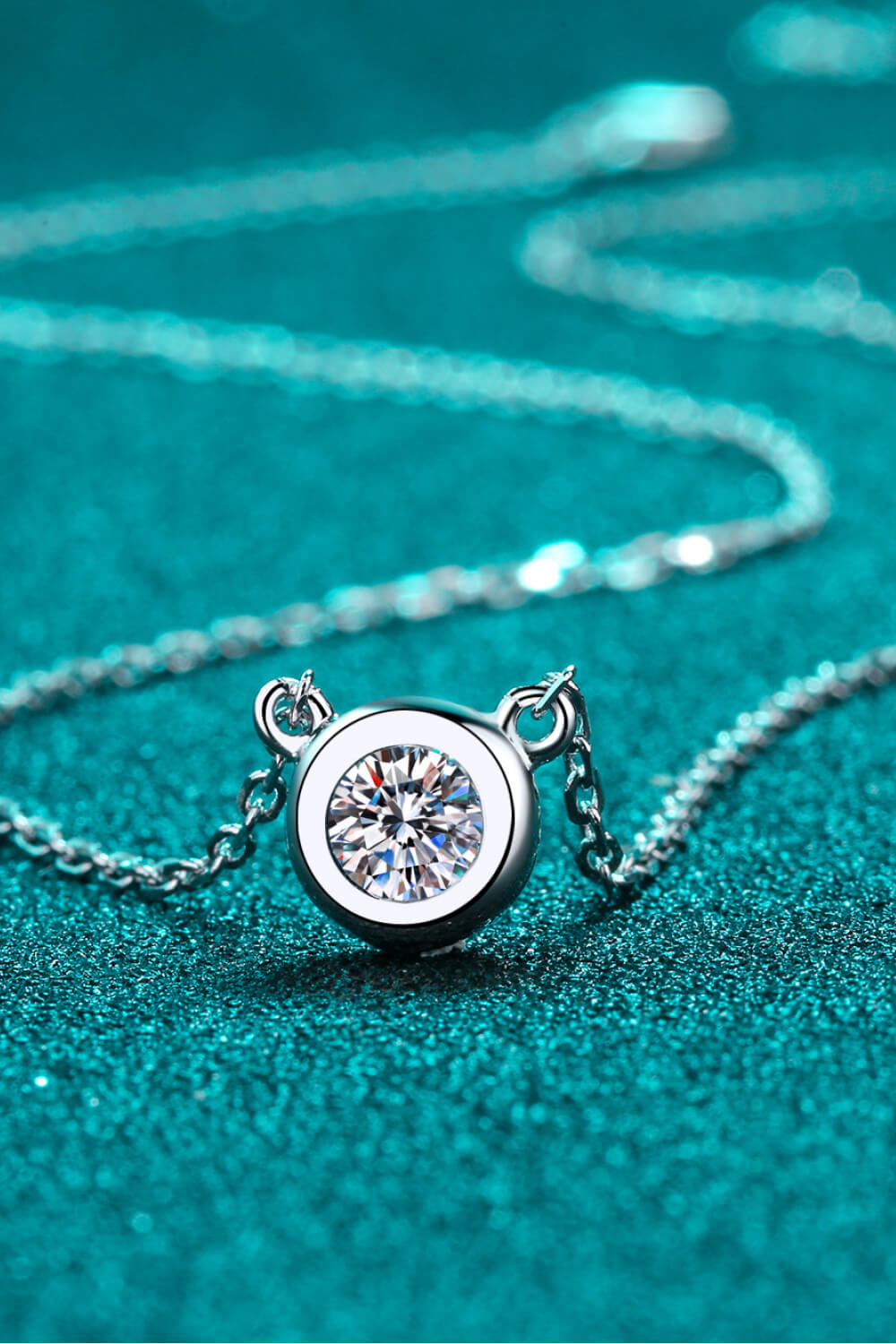 Silver solitaire bezel-set diamond necklace with a delicate chain.