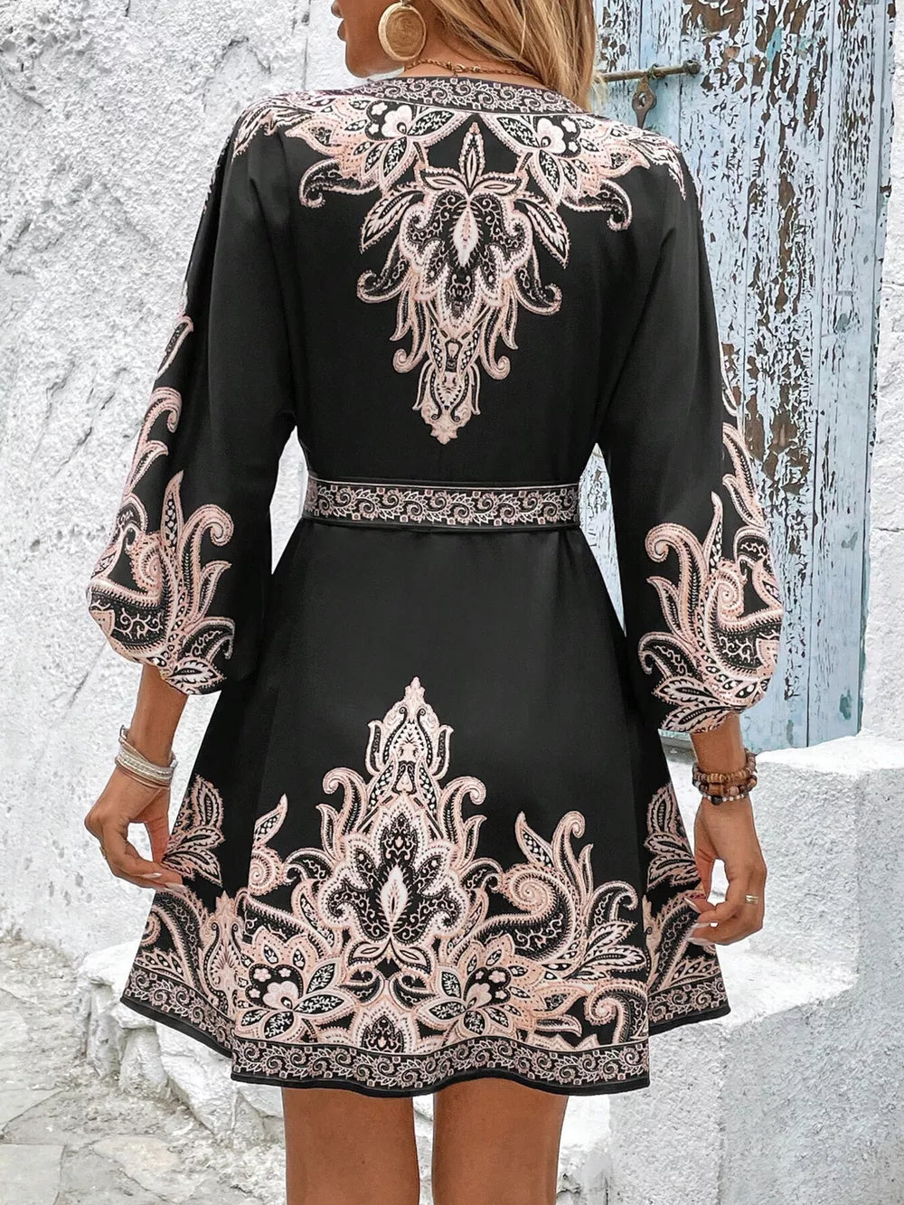Black mini dress with pink paisley print, billowy sleeves, and waist tie.