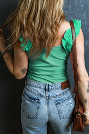 Light green ribbed tank top with ruffled straps, styled with denim jeans.