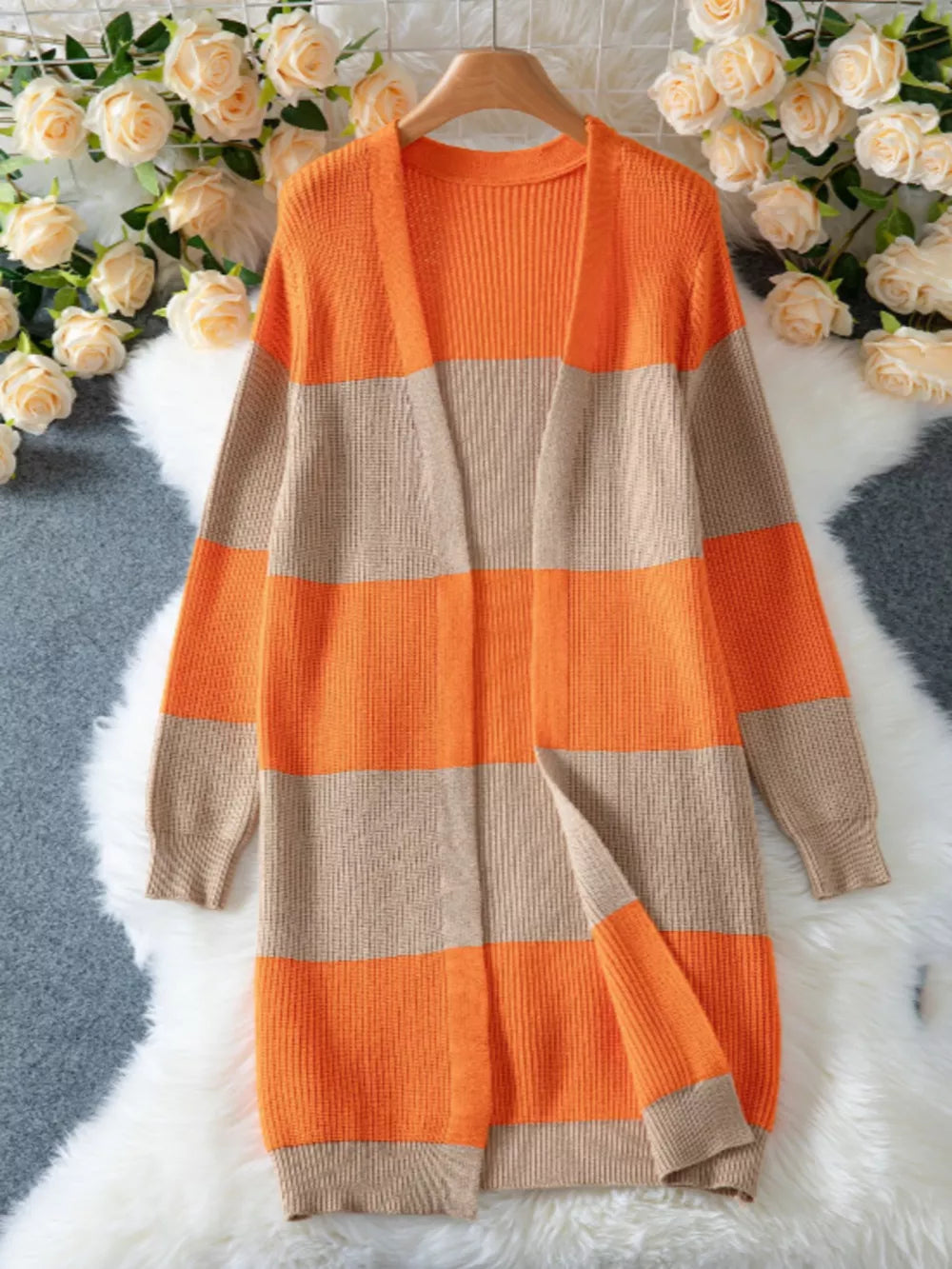 Long color block knit cardigan with orange and beige stripes, open front, ribbed texture.