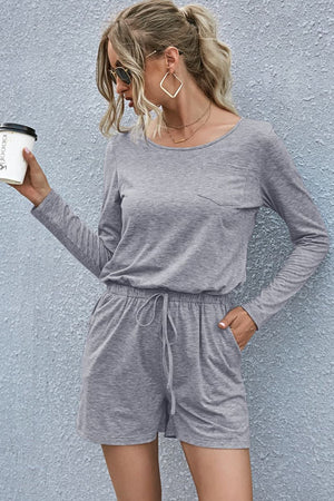 Gray jersey romper with long sleeves, chest pocket, drawstring waist, and pockets.