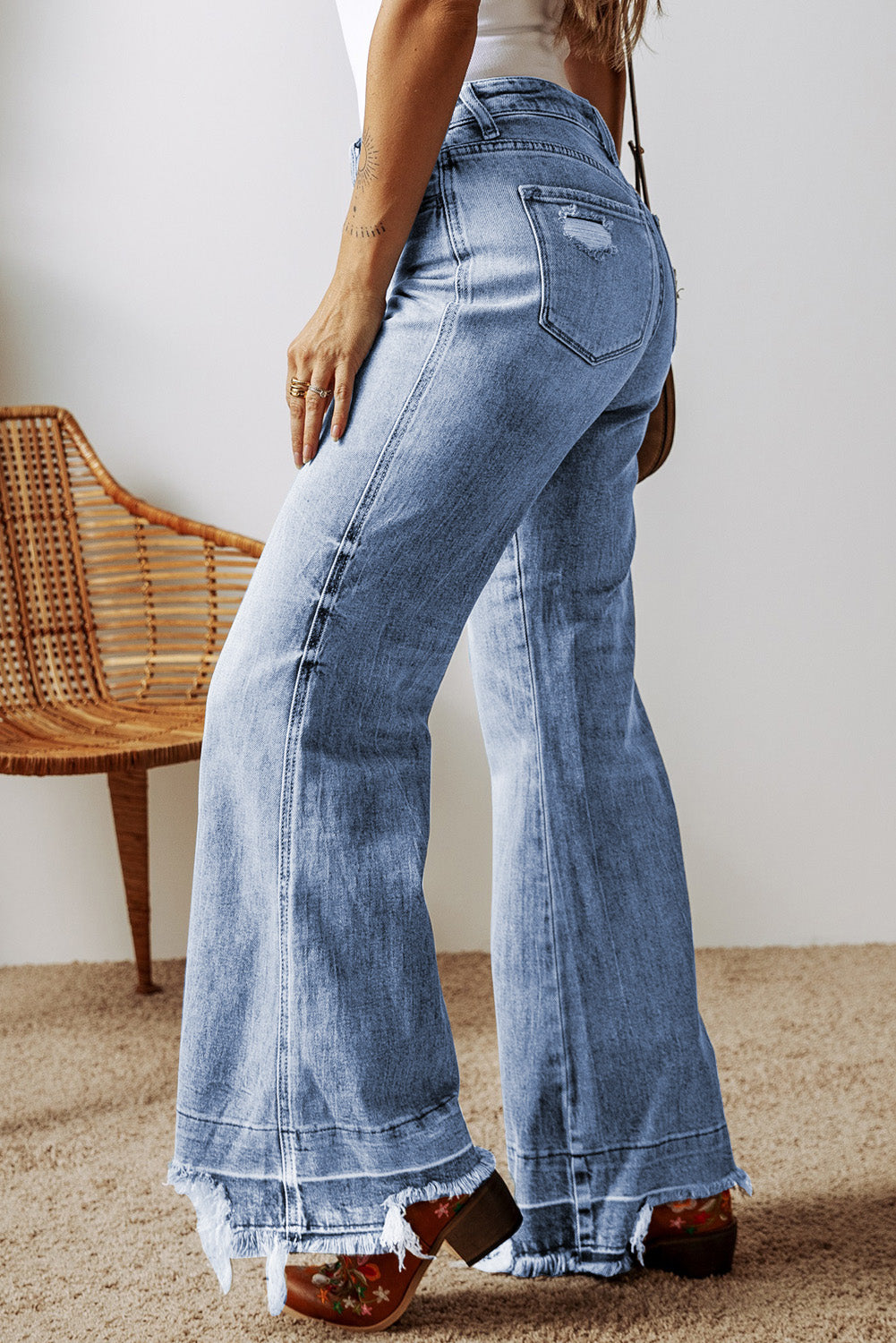 Medium wash denim flare jeans with raw hem and distressed pocket detail.