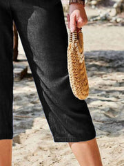 Black cropped denim trousers with elastic waist and a relaxed fit.