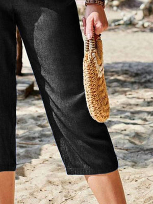 Black cropped denim trousers with elastic waist and a relaxed fit.
