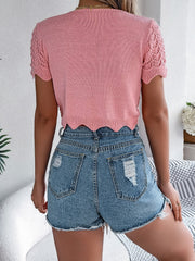 Pale blush crochet knit top with scalloped hem and short sleeves, paired with distressed denim shorts.