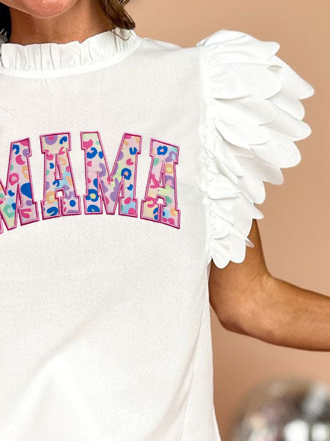 White Mama blouse with appliqué letters and ruffled flutter sleeves.