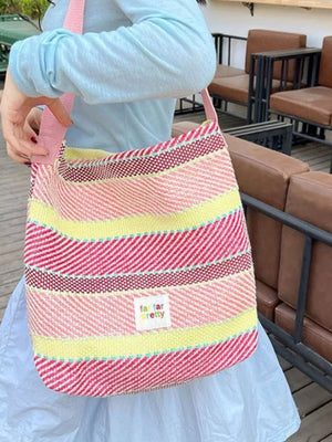 Vibrant striped woven shoulder bag with pink strap and a small embroidered patch.