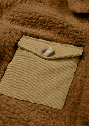 Brown sherpa coat with a tan corduroy patch pocket and button detail.