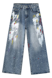 Painterly wash wide-leg denim trousers in medium blue with artistic paint splatters and brushstrokes.