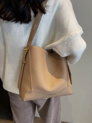Khaki pebbled leather crossbody bag with adjustable strap and gold buckle detail.