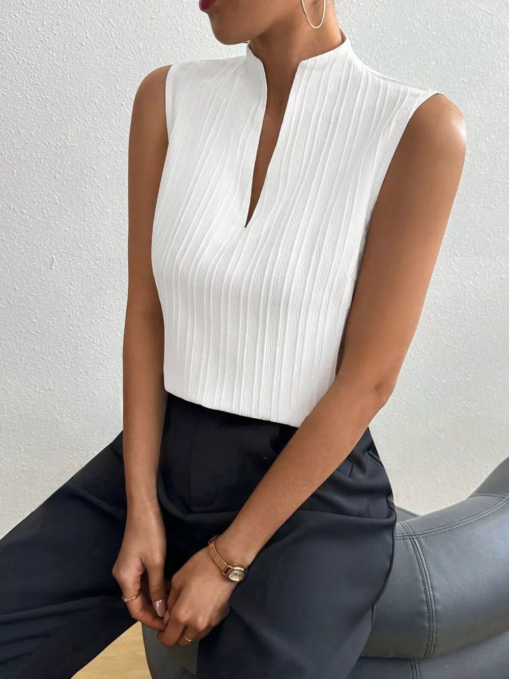White textured sleeveless blouse with notched V-neck.