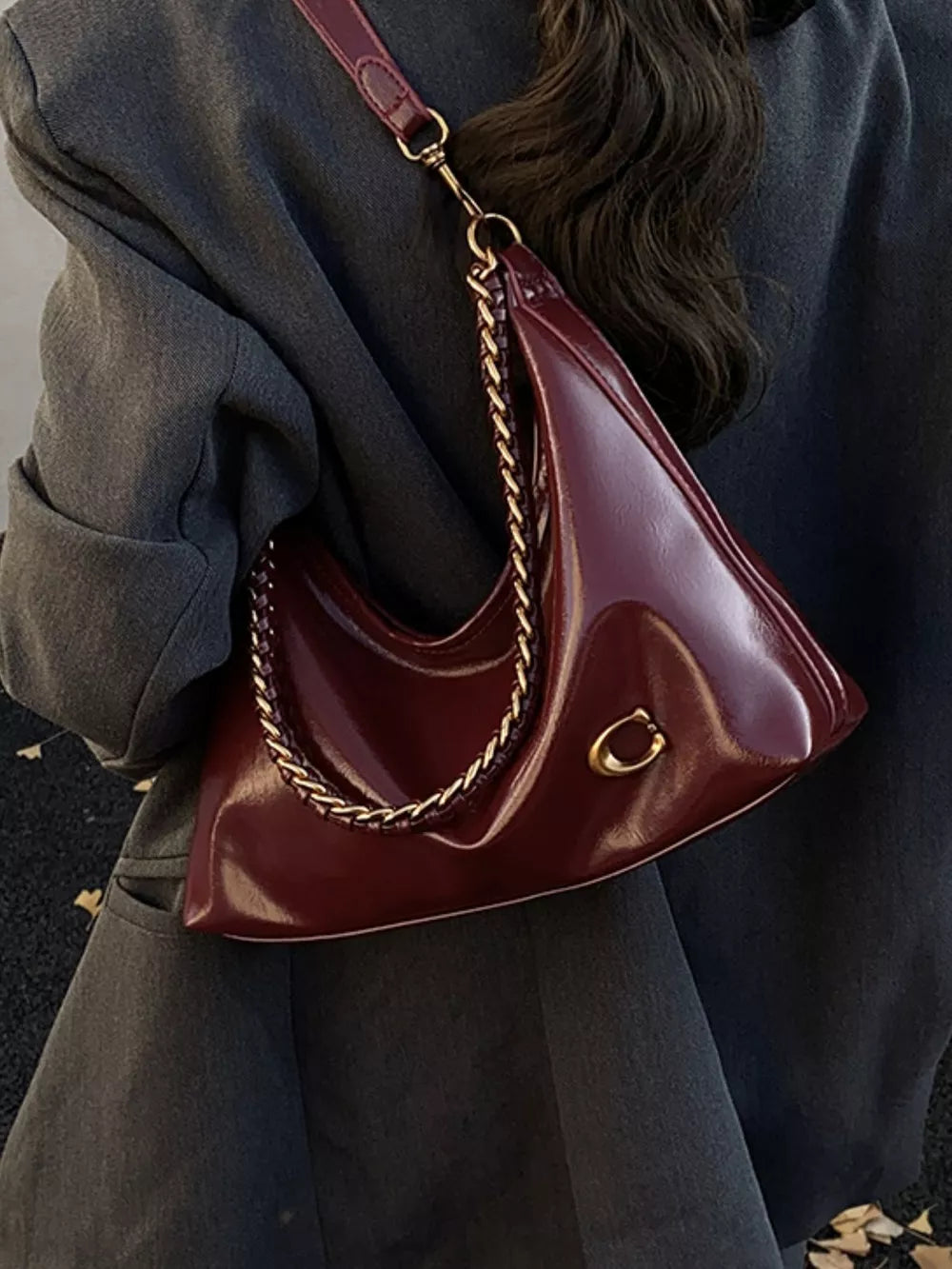Chic crescent shoulder bag in glossy brown with gold chain strap and hardware.