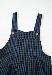 Dark blue gingham overalls with button detail on straps and pleated skirt.