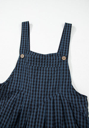 Dark blue gingham overalls with button detail on straps and pleated skirt.