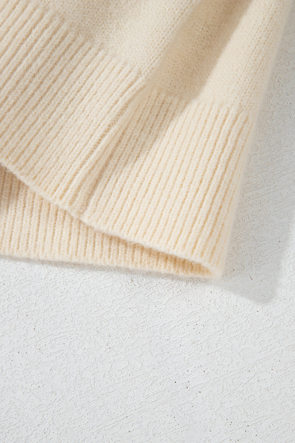 Ivory bouclé knit cardigan with tie-front detail and ribbed cuffs.